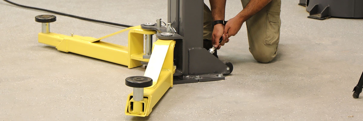 MaxJax two-post lift secures with five recessed anchor bolts per column for safe lifting and easy storage.